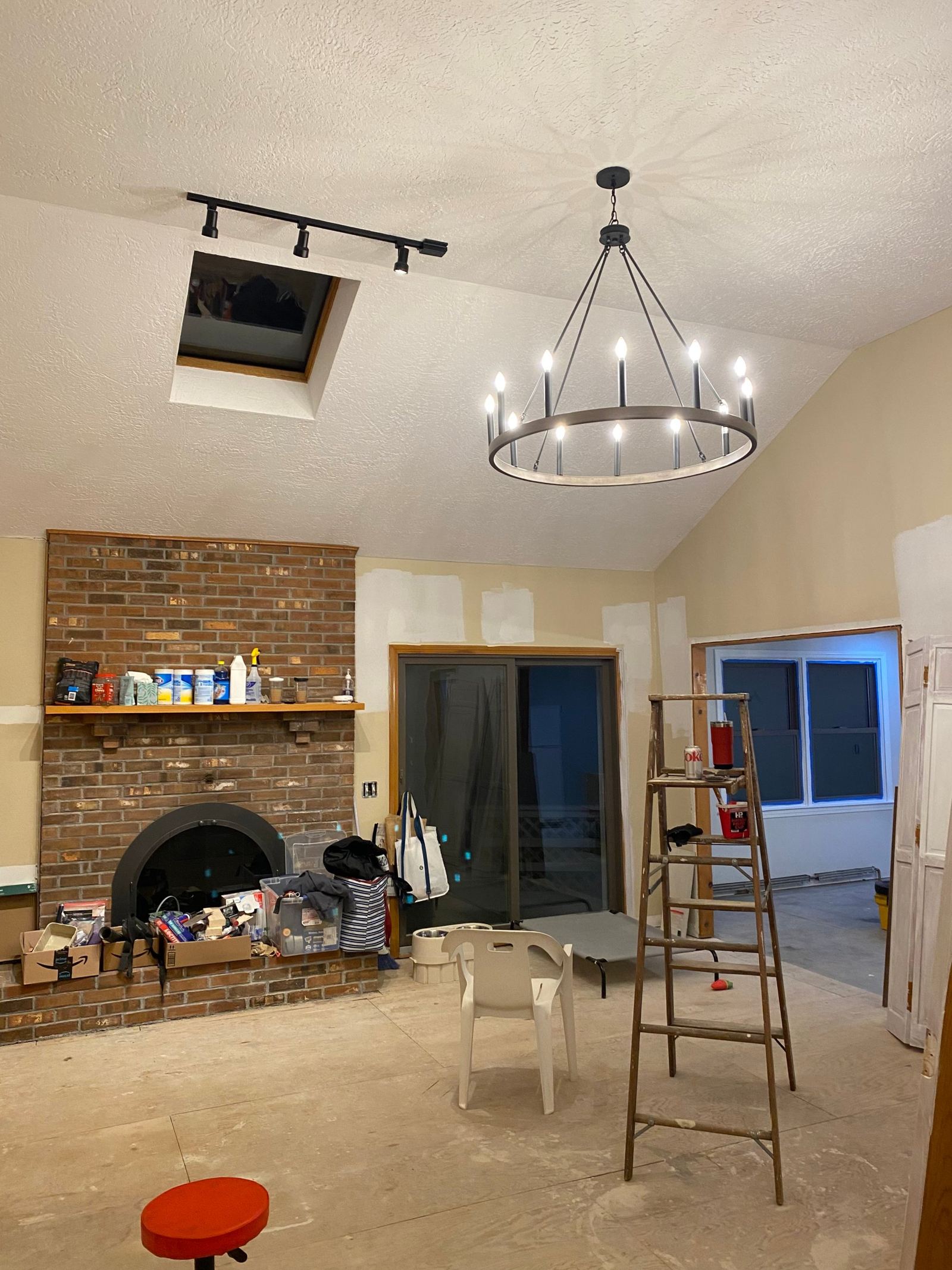 Wagon-wheel chandelier and track lighting under a vaulted ceiling with a skylight